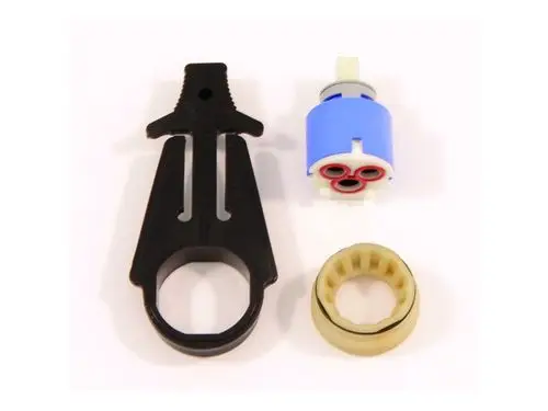 Drei Bauteile einer Kartusche von Ideal Standard: ein schwarzes Kunststoffwerkzeug, ein blauer Zylinder mit roten Elementen und ein beigefarbener Ring.
